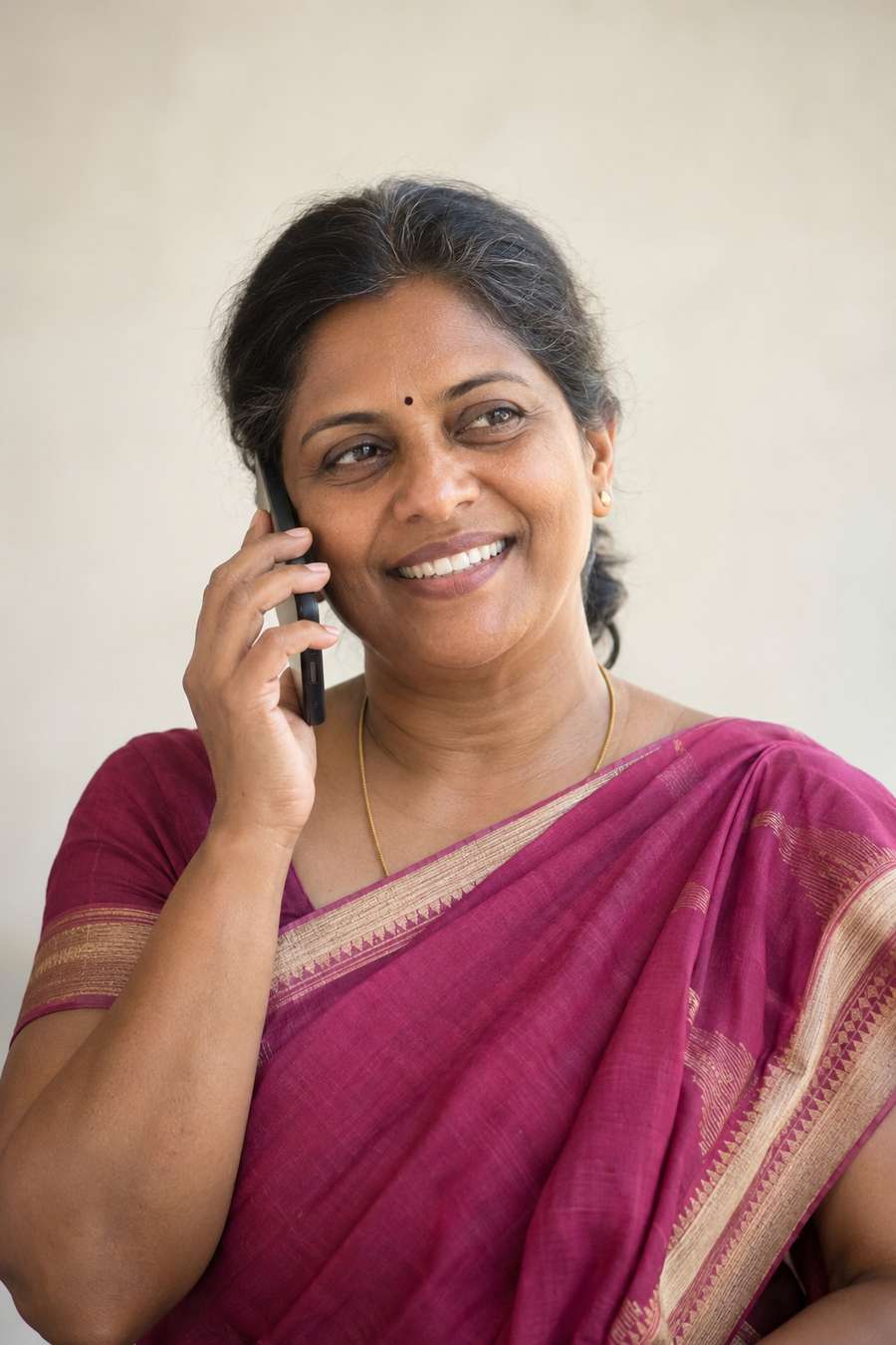 Illustrative portrait of a middle-aged Indian woman in a magenta sari smiling while talking on the phone